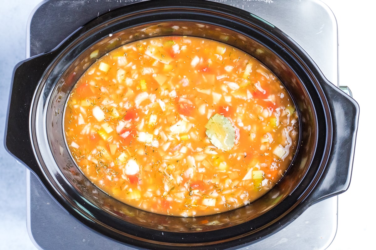 adding ingredients to slow cooker for lentil soup
