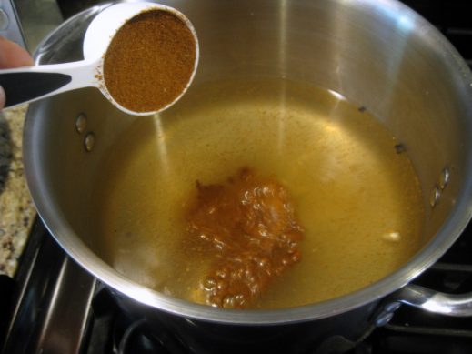 pouring old bay seasoning into vinegar in a large soup pot to make old bay shrimp