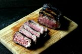 grilled steak cut into pieces on a wood cutting board