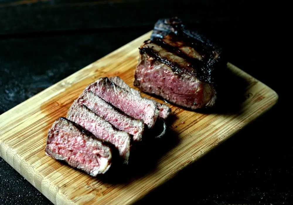 grilled steak cut into pieces on a wood cutting board