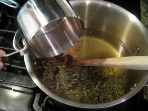 pouring loose tea into a pot with water for homemade kombucha