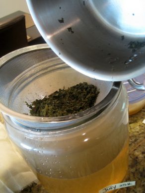 straining tea leaves to home brew kombucha