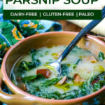 ceramic bowl of parsnip soup with greens and a old looking spoon