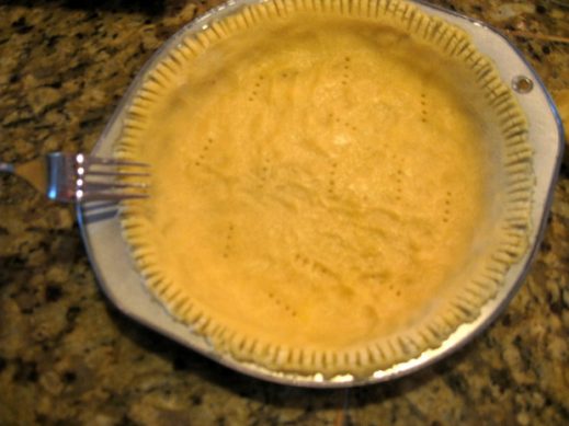 using a fork to make indents along the outer crust of uncooked paleo pie crust dough in a pie pan