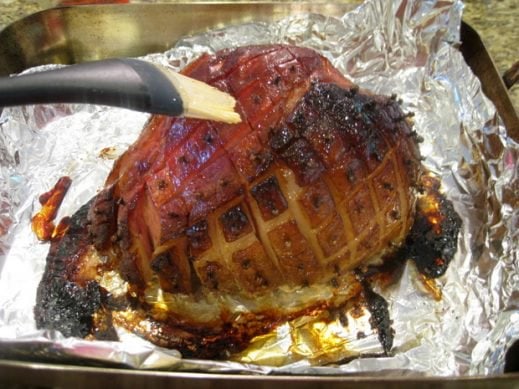 basting a smoked spiced whole ham with maple syrup