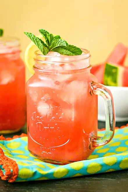 close up of watermelon cocktail topped with mint and lemon