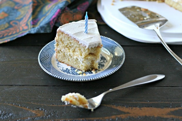 slice of vanilla birthday cake with vanilla frosting and blue candle