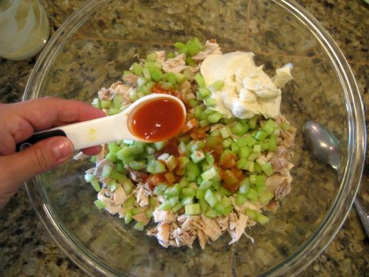 mixing ingredients for Buffalo Chicken Salad in a glass bowl