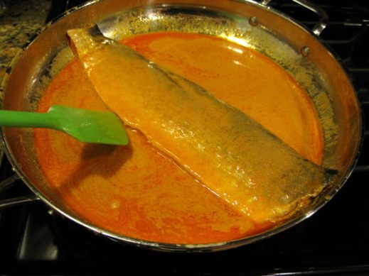 cooking whole salmon fillet in thai red curry paste in a large skillet