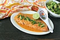 platter of cooked wild salmon with red curry sauce, lime and sliced scallions