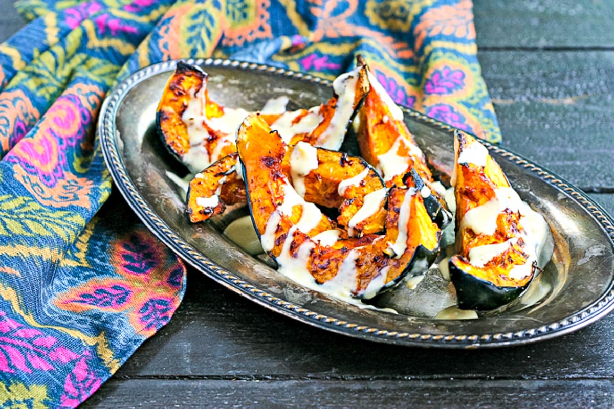 roasted acorn squash with tahini drizzle on a serving platter