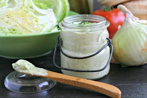 glass jar with garlic chive mayonnaise in front of lettuce