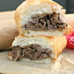 close up of Philly Cheese Steak Sandwich cut in half and stacked on wax paper