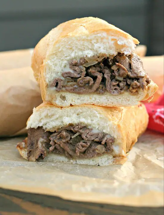 close up of Philly Cheese Steak Sandwich cut in half and stacked on wax paper