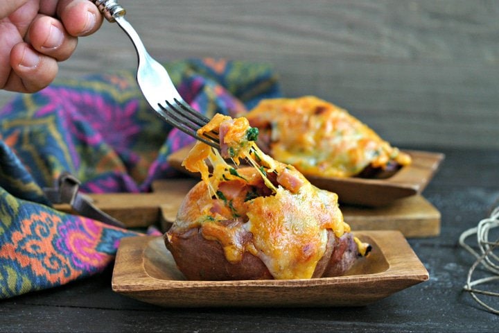 melted cheese being pulled by a fork from leftover ham stuffed sweet potato