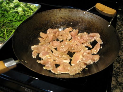 stir frying chicken slices in a wok