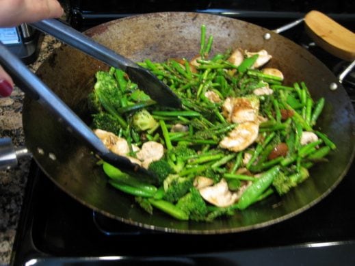mixing chicken and vegetables with sauce in the wok
