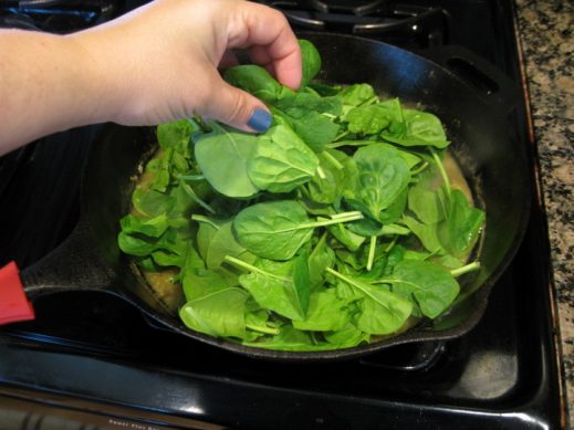 adding baby spinach to lemon garlic sauce in cast iron pan