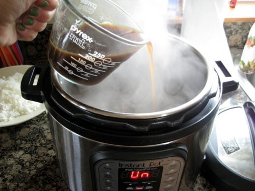 pouring sauce mixture for beef and broccoli into steaming Instant Pot