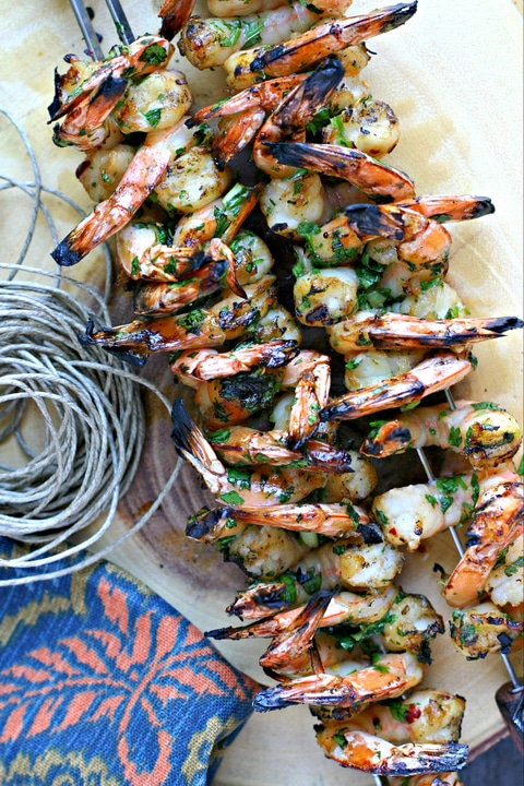 shrimp on skewers on a wood platter with piece of twine and napkin