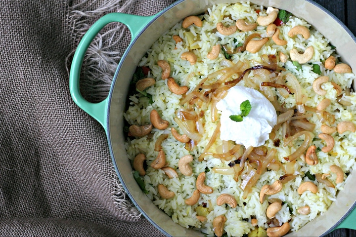 Green Le Creuset Pot with Veggie and Rice Biryani topped with cashews and yogurt