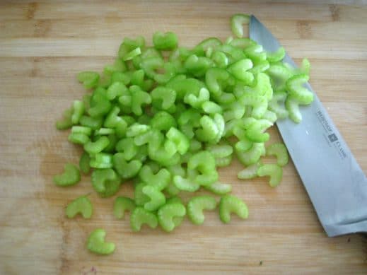 thinly sliced celery pieces with a sharp knife on a wood cuttin board