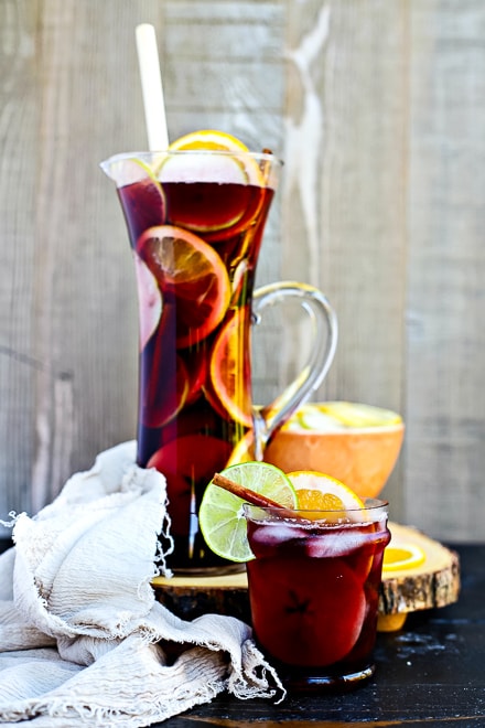 large glass pitcher of fall sangria with sliced fruit