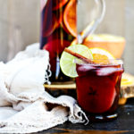 close up of red sangria with ice in front of glass pitcher