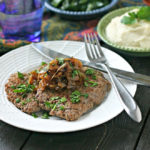 close up of cooked cube steak with bowl of mashed potatoes