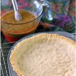 baked paleo pie crust sitting on a wire cooling rack with pumpkin pie filling and linen in the background