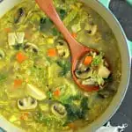 overhead shot of large soup pot with easy turkey soup with cabbage and turmeric with wood ladle and beige linen