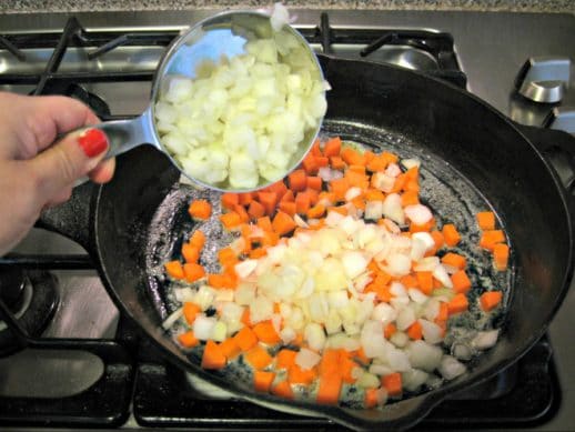 adding chopped onion and carrot to a cast iron skillet to make easy shepherd's pie