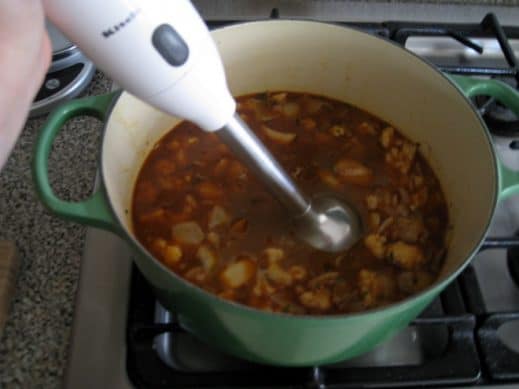 using an immersion blender to puree Garlic Soup in a large soup pot on the stove