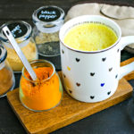 mug of golden milk with jars of spices