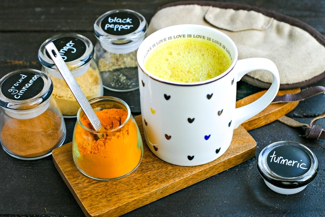 mug of turmeric milk with jars of spices and a sleeping mask