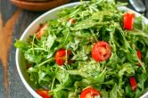 close up of white serving bowl with arugula salad