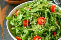 close up of white serving bowl with arugula salad