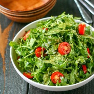 close up of white serving bowl with arugula salad