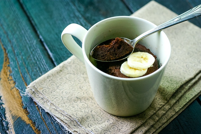 single serving chocolate mug cake topped with sliced bananas with a spoon
