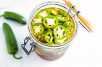 a glass jar stuffed with homemade pickled jalapenos