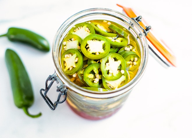 a glass jar stuffed with homemade pickled jalapenos
