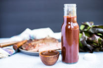 glass bottle of A1 steak sauce in front of cooked steak