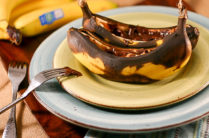 baked bananas on a plate topped with melted peanut butter and chocolate