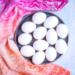 close up of white eggs on a gray platter with colorful linen for coddled eggs