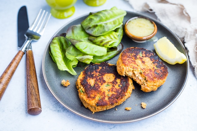 plate of salmon cakes with lemon, lettuce, and dipping sauce