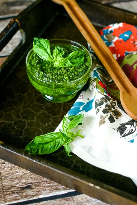 vegan pesto in small dish with fresh basil on a serving tray