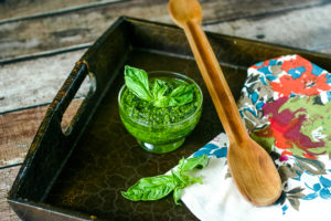 Vegan pesto in a small dish with fresh basil and wood spoon