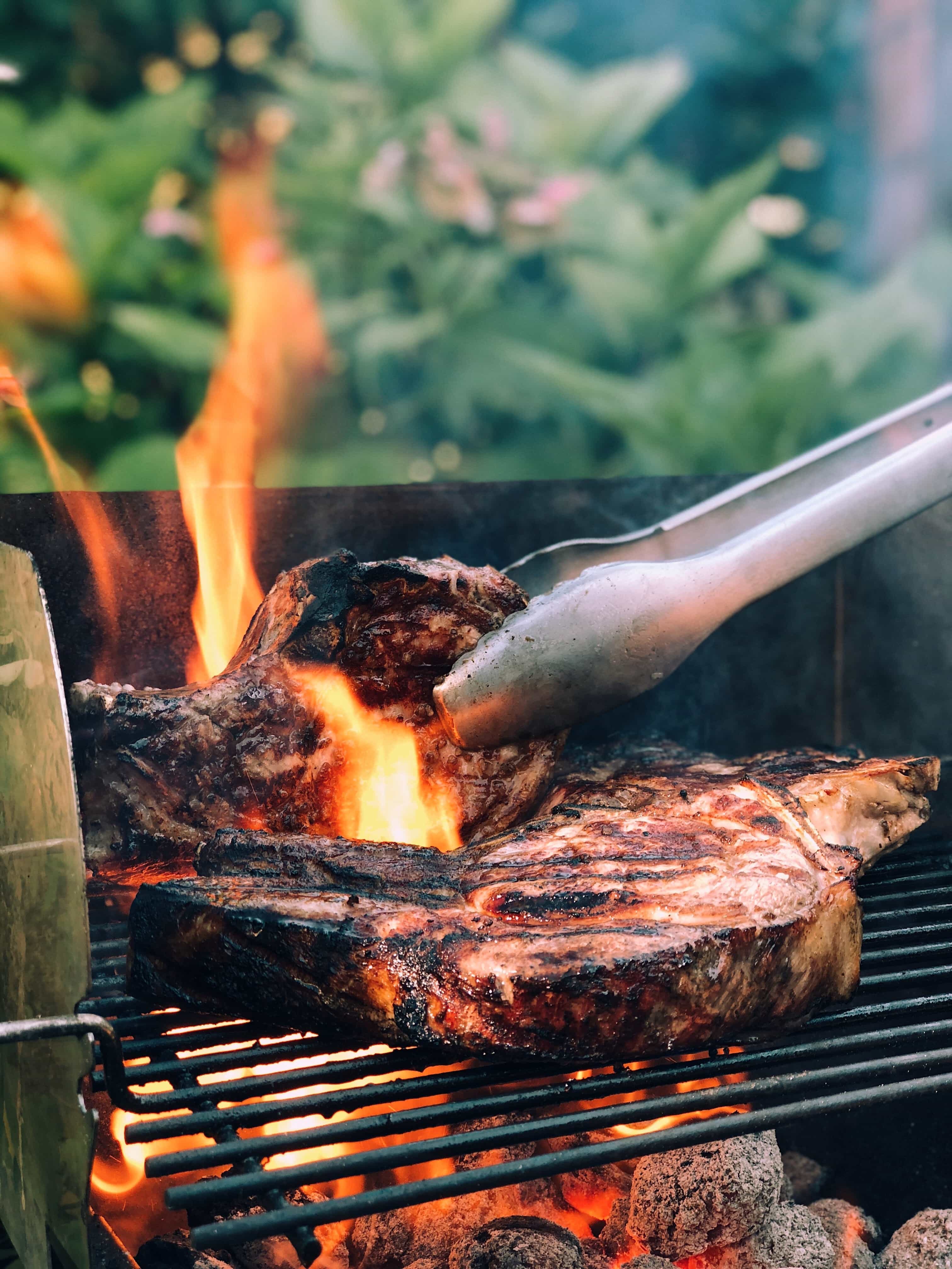 grilling steaks on a grill with a large flame