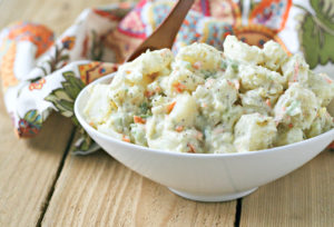 white bowl of classic potato salad on a wood table