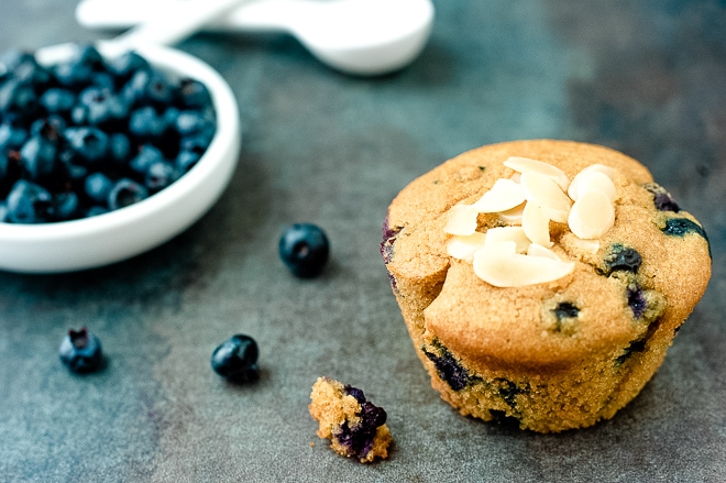 paleo blueberry muffin on a counter with fresh blueberries